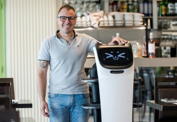 Geoffrey Ruamps, directeur du restaurant le Cap 180, pose avec le robot serveur "Bella" dans son restaurant, à Cieurac, dans le Lot, le 14 mai 2024