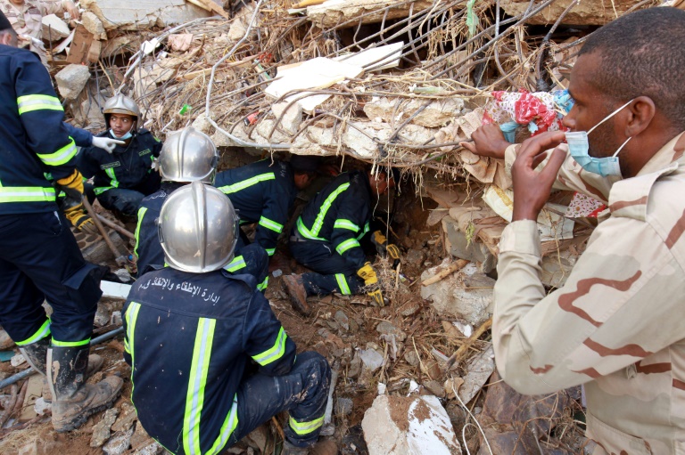 Pompiers et secouristes cherchant des survivants dans les décombres d'un immeuble effondré lors des inondations provoquées par la tempête qui a frappé la ville de Derna, dans l'est de la Libye, le 14 septembre 2023