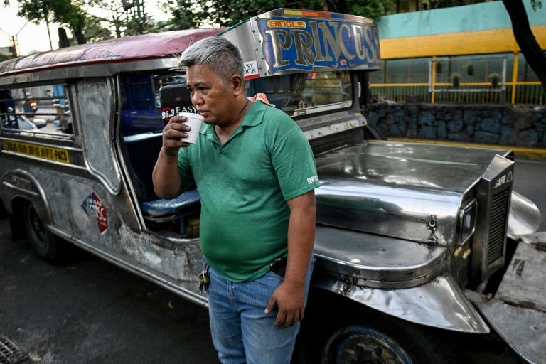 Le chauffeur de jeepney Eric Helera boit un café pendant une pause avant de prendre la route à Manille, le 23 mars 2026