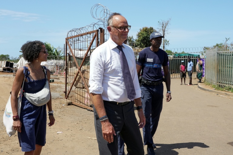 Édouard Philippe (c), fondateur et président du parti Horizons, maire du Havre et candidat à l'élection présidentielle, et Ambdilwahedou Soumaila (g), maire de Mamoudzou visitent une rue commerçante de Mamoudzou, le 21 août 2026 sur l'île de Mayottte