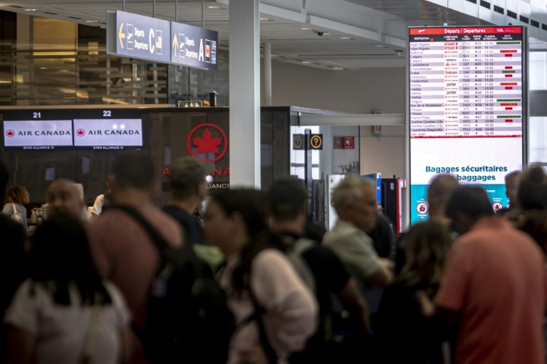 Des voyageurs consultent un panneau d'information sur les vols annulés d'Air Canada à l'aéroport Pierre-Elliott Trudeau à Montréal, au Québec, le 17 août 2025 au Canada