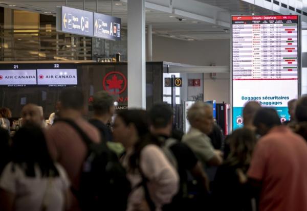 Des voyageurs consultent un panneau d'information sur les vols annulés d'Air Canada à l'aéroport Pierre-Elliott Trudeau à Montréal, au Québec, le 17 août 2025 au Canada