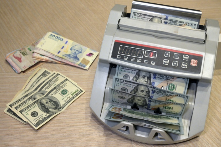 Des billets de pesos argentins et des billets de dollars américains à Buenos Aires, le 22 octobre 2025 en Argentine