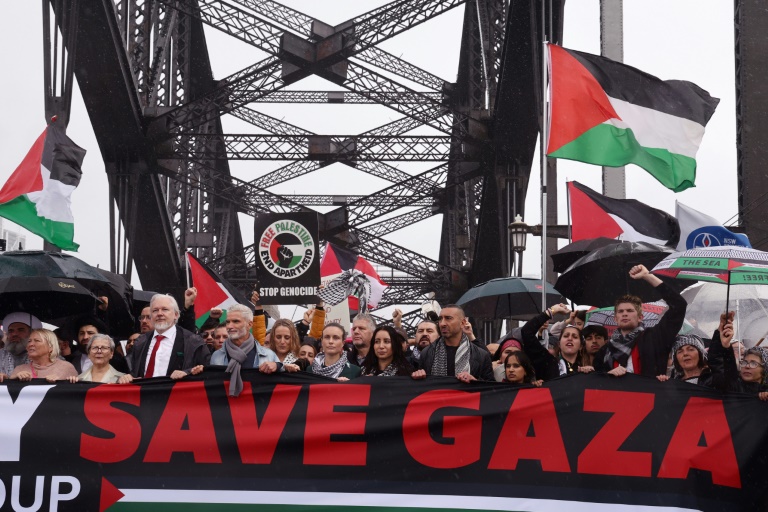 Des manifestants, dont le fondateur de WikiLeaks, Julian Assange (3e en partant de la gauche, l'homme portant une cravate rouge), défilent sur le pont Harbour Bridge à Sydney lors d’un rassemblement pro-palestinien le 3 août 2025.