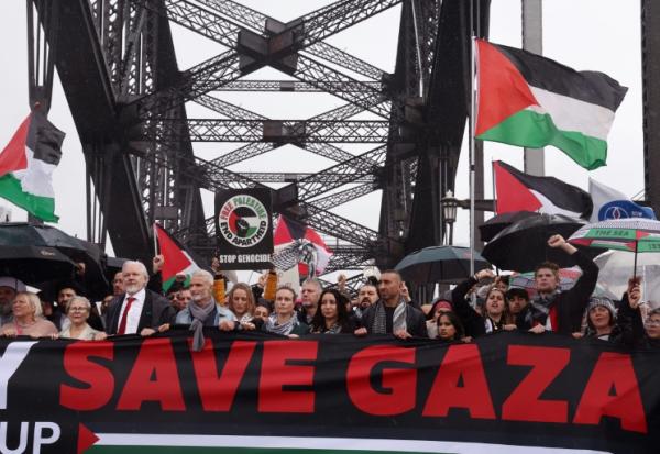Des manifestants, dont le fondateur de WikiLeaks, Julian Assange (3e en partant de la gauche, l'homme portant une cravate rouge), défilent sur le pont Harbour Bridge à Sydney lors d’un rassemblement pro-palestinien le 3 août 2025.