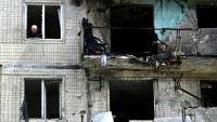 Un habitant à la fenêtre de son appartement dans un immeuble résidentiel endommagé par une frappe de drone russe sur Kiev, le 24 mai 2025 en Ukraine