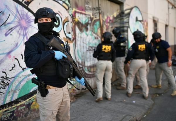 Des policiers pénètrent dans une habitation lors d'une opération antidrogue   à Santiago, le 11 décembre 2025 
