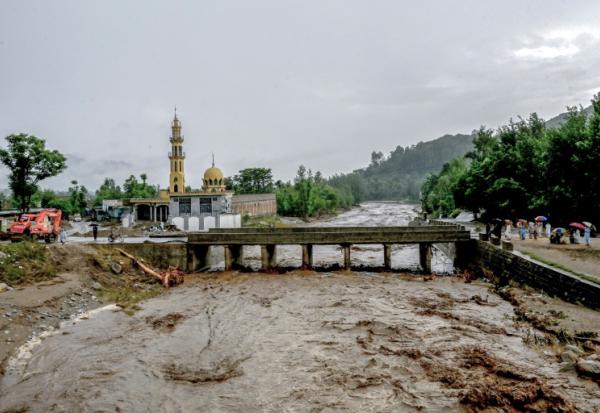 Des villageois (d) se tiennent près d'un pont alors que le niveau des eaux de crue monte dans le district de Buner, dans la province  de Khyber Pakhtunkhwa, le 18 août 2025 au Pakistan