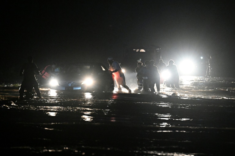 Des villageois arpentent des rues inondées dans le village de Dolari, dans le nord du Pakistan, à la recherche de survivants ou de corps de victimes des violentes pluies de mousson, le 18 août 2025
