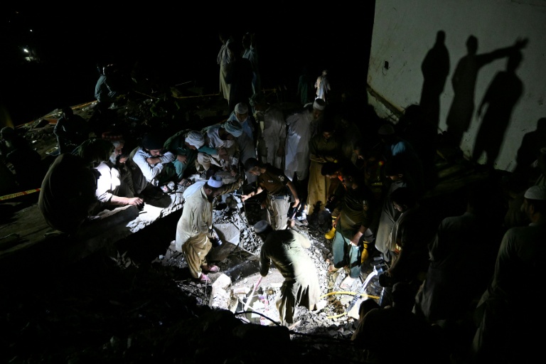 Sans électricité, des villageois et secouristes fouillent les décombres de maisons dévastées par la mousson, à la recherche de survivants ou de dépouilles de victimes, dans le village de Dolari, dans le nord du Pakistan, le 18 août 2025
