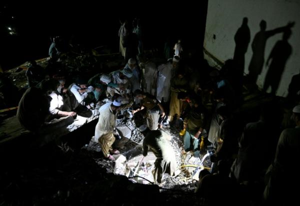 Sans électricité, des villageois et secouristes fouillent les décombres de maisons dévastées par la mousson, à la recherche de survivants ou de dépouilles de victimes, dans le village de Dolari, dans le nord du Pakistan, le 18 août 2025
