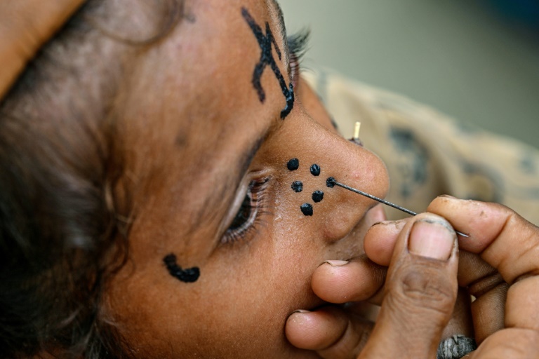 Un tatouage traditionnel est dessiné sur le visage de la jeune Champa, 7 ans, à la colonie Jogi à Umerkot, un district à majorité hindoue, le 14 juillet 2025 au Pakistan