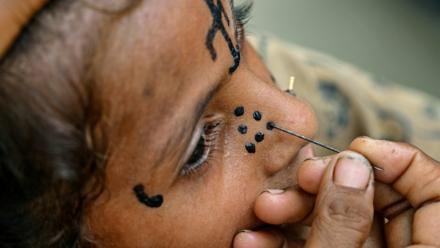 Un tatouage traditionnel est dessiné sur le visage de la jeune Champa, 7 ans, à la colonie Jogi à Umerkot, un district à majorité hindoue, le 14 juillet 2025 au Pakistan