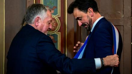 Le maire réélu Grégory Doucet, à droite, reçoit son écharpe des mains de Jean-Michel Aulas, à gauche, le 27 mars 2026, à Lyon