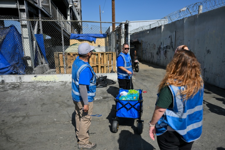 Armando Covarrubias (au centre) et ses collègues de l'association Hope The Mission distribuent de l'eau et de la nourriture dans un campement de sans-abris à Los Angeles, le 1er juin 2026