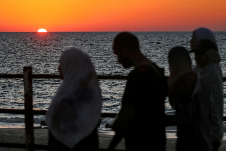 Le soleil se couche sur la mer Méditerranée alors que des Palestiniens déplacés évacuent la ville de Gaza vers le sud de la bande de Gaza face aux bombardements israéliens, le 13 septembre 2025 dans la bande de Gaza