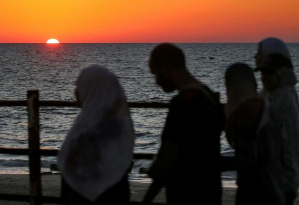 Le soleil se couche sur la mer Méditerranée alors que des Palestiniens déplacés évacuent la ville de Gaza vers le sud de la bande de Gaza face aux bombardements israéliens, le 13 septembre 2025 dans la bande de Gaza