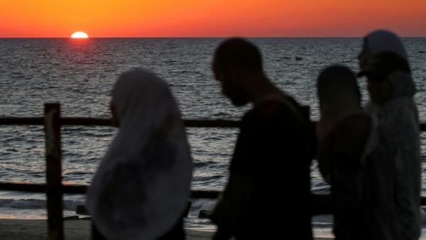 Le soleil se couche sur la mer Méditerranée alors que des Palestiniens déplacés évacuent la ville de Gaza vers le sud de la bande de Gaza face aux bombardements israéliens, le 13 septembre 2025 dans la bande de Gaza