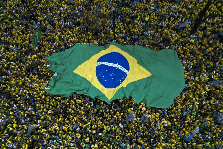 Des partisans de Flavio Bolsonaro, candidat du Parti libéral (PL) à la présidentielle, brandissent un immense drapeau brésilien lors d'un rassemblement à São Paulo, le 18 octobre 2026 au Brésil, avant le second tour de l'élection