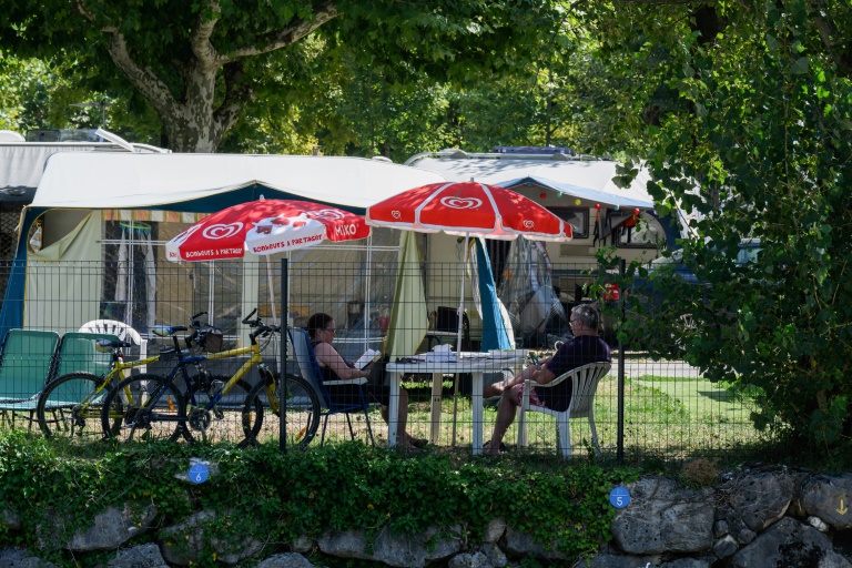 Des vacanciers assis à l'ombre dans un camping au Bourget-du-Lac, le 8 août 2025 en Savoie