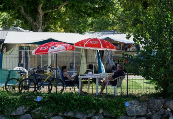 Des vacanciers assis à l'ombre dans un camping au Bourget-du-Lac, le 8 août 2025 en Savoie