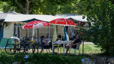 Des vacanciers assis à l'ombre dans un camping au Bourget-du-Lac, le 8 août 2025 en Savoie