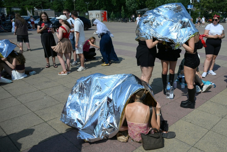 Des spectateurs se protègent de la chaleur  avec des couvertures de survie avant un concert de Bruo Mars à l'Olympic stadium de Berlin, le 28 juin 2026 en Allemagne