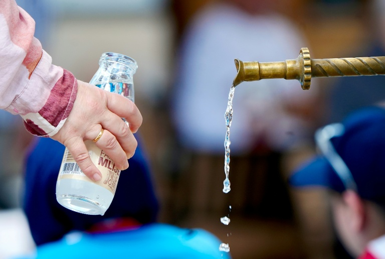 Une femme remplit une bouteille avec l'eau d'une fontaine dans le centre historique de Sarajevo pendant une vague de chaleur, le 26 juin 2026 en Bosnie