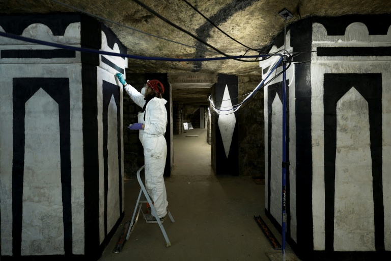 Un restaurateur d'art travaille sur un tableau pendant des travaux de restauration des Catacombes de Paris, le 24 mras 2026