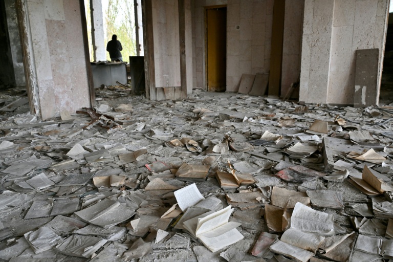 Un visiteur marche parmi des livres jonchant le sol du Palais de la culture, abandonné, dans la ville fantôme de Pripyat, près de la centrale nucléaire de Tchernobyl, le 23 avril 2026