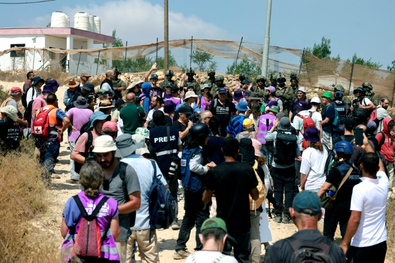 Des Palestiniens et des militants rassemblés pour manifester contre des colons israéliens qui assiègent la maison d'une famille palestinienne dans le village de Qusra, au sud de la ville de Naplouse, en Cisjordanie occupée, le 14 août 2026