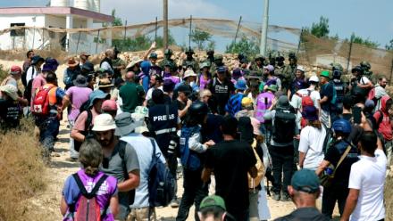 Des Palestiniens et des militants rassemblés pour manifester contre des colons israéliens qui assiègent la maison d'une famille palestinienne dans le village de Qusra, au sud de la ville de Naplouse, en Cisjordanie occupée, le 14 août 2026
