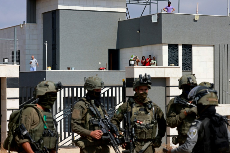 Des soldats israéliens devant l'entrée d'une maison palestinienne assiégée par des colons israéliens dans le village de Qusra, au sud de Naplouse, en Cisjordanie occupée, le 14 août 2026