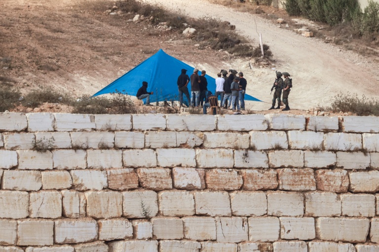 Des soldats israéliens près d'une tente installée par des colons israéliens devant l'entrée de la maison d'une famille palestinienne assiégée, dans le village de Qusra, au sud de la ville de Naplouse, en Cisjordanie occupée, le 14 août 2026