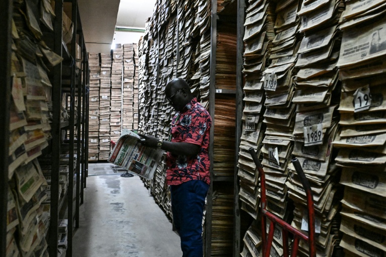 Jean-Baptiste Adoule, archiviste, examine un journal dans les archives du journal gouvernemental Fraternité Matin à Adjamé, un quartier populaire d'Abidjan (Côte d'Ivoire), le 9 juin 2026