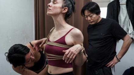 Une jeune femme attache les bras de sa modèle sous les yeux de Hajime Kinoko, l'un des plus connus artistes japonais de "shibari", l'art des cordes, le 26 mai 2025 à Tokyo