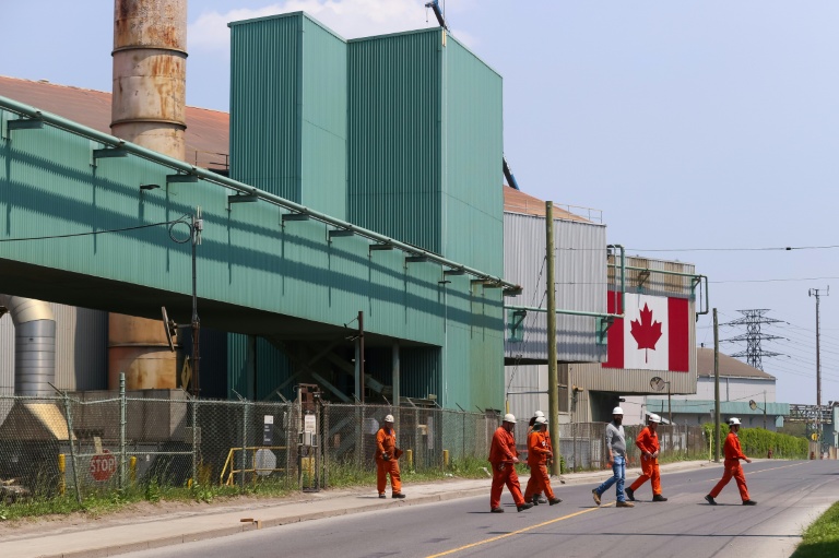 Des travailleurs sortent des bâtiments de fabrication d'acier d'ArcelorMittal Dofasco à Hamilton, en Ontario, le 4 juin 2025 au Canada