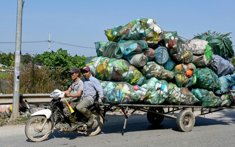 Deux hommes tractent à moto des déchets en plastique destinés à être recyclés aux alentours de Hanoï, au Vietnam, le 25 novembre 2025