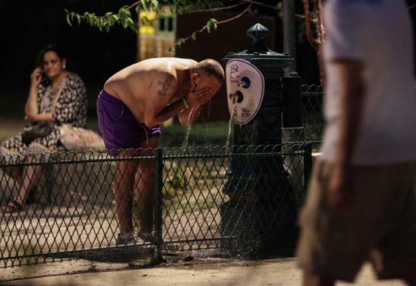 Un homme se rafraîchit à une fontaine publique près du Canal Saint-Martin à Paris en pleine canicule, le 25 juin 2026