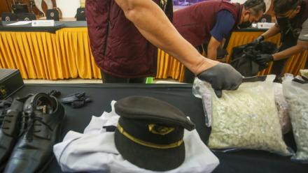 Des agents des douanes présentent l'uniforme d'un pilote ainsi que la drogue qu'il a fait passer en contrebande, lors d'une conférence de presse à l'aéroport international Soekarno-Hatta de Tangerang, près de Jakarta, le 31 juillet 2026 en Indonésie