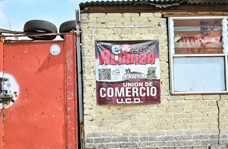 Une affiche sur le mur d'une entreprise indique un signe d'affiliation payante à des groupes qui garantissent la sécurité contre l'extorsion à Ecatepec, dans l'État de Mexico, le 2 octobre 2025
