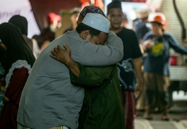 Des proches des écoliers disparus se confortent pendant que les opérations de recherche et de sauvetage se poursuivent à l'internat islamique Al Khoziny à Sidoarjo, dans la province de Java oriental, le 1er octobre 2025