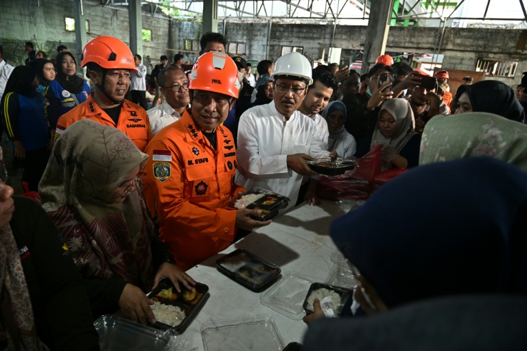 Mohammad Syafii (C), chef de l'Agence nationale de recherche et de sauvetage de l'Indonésie, accompagné de Saifullah Yusuf (centre D), ministre des Affaires sociales, inspecte une distribution de nourriture pour les proches des écoliers portés disparus après l'effondrement de l'école religieuse islamique Al Khoziny à Sidoarjo, dans la province de Java oriental, le 1er octobre 2025