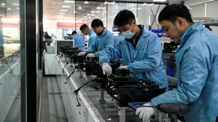 Des ouvriers travaillent sur une ligne de production de l'usine Neolix qui fabrique de petits véhicules utilitaires autonomes pour le transport de colis en ville, le 4 décembre 2025 à Yancheng dans la province chinoise du Jiangsu 