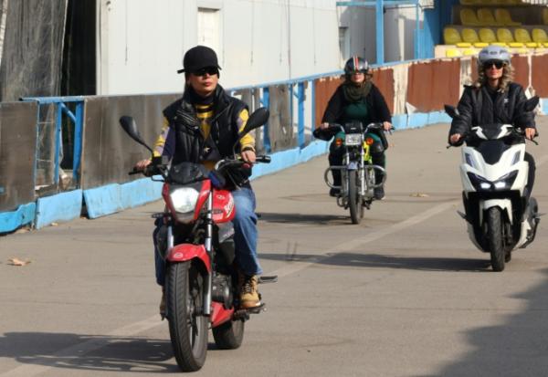 La monitrice Maryam Ghelich (g) guide les élèves Elham (c) et Mona sur leurs scooters dans un centre d'entraînement du nord de Téhéran, le 7 décembre 2025 en Iran
