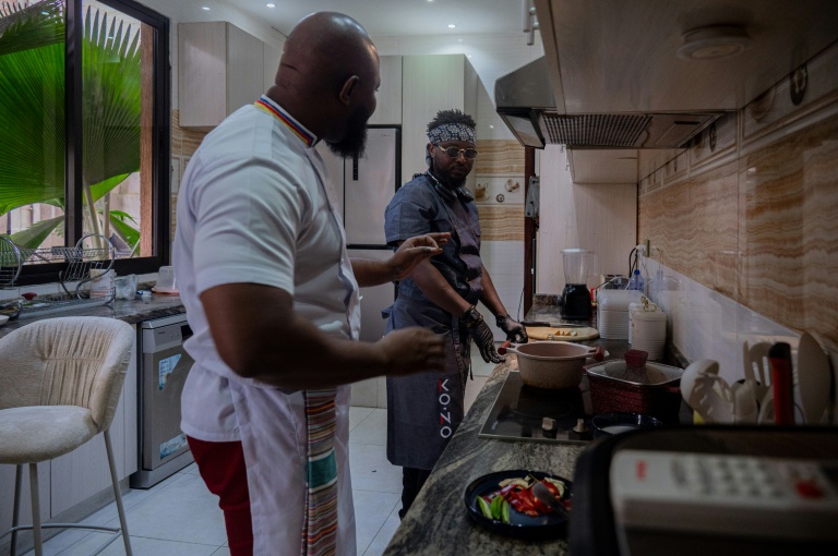Le chef congolais Archi Dimosi parle avec son sous-chef lors de la préparation d'un plat dans sa cuisine, le 17 mai 2026 à Kinshasa, en RDC