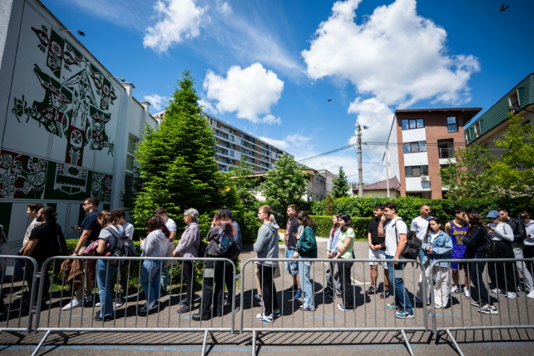 Des étudiants font la queue devant un bureau de vote pour le second tour de la présidentielle roumaine, le 18 mai 2025 à Bucarest