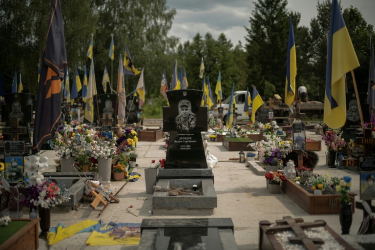 La tombe d'un soldat, entourée de drapeaux aux couleurs ukrainiennes, dans une des allées réservées aux soldats tués au combat contre les forces russes, dans le cimetière de Sumy, dans le nord-est de l'Ukraine, le 11 juin 2025