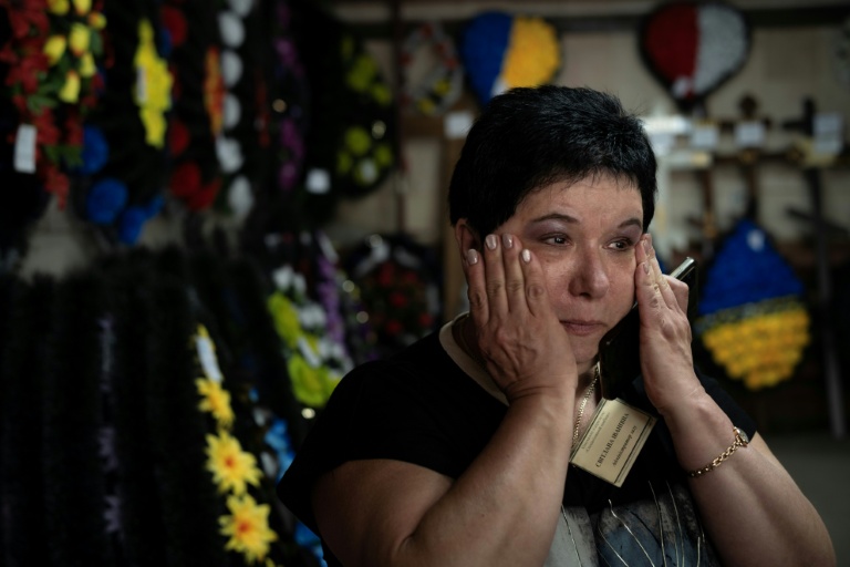 Svitlana Ostapenko, gérante du funérarium de Sumy, dans le nord-est de l'Ukraine, prépare, le 11 juin 2025, une croix et un couronne mortuaire pour l'enterrement d'un jeune soldat tué récemment lors de combats contre les forces russes