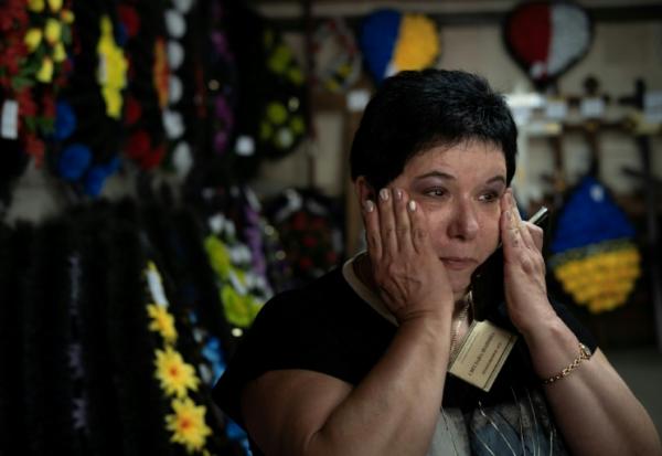 Svitlana Ostapenko, gérante du funérarium de Sumy, dans le nord-est de l'Ukraine, prépare, le 11 juin 2025, une croix et un couronne mortuaire pour l'enterrement d'un jeune soldat tué récemment lors de combats contre les forces russes